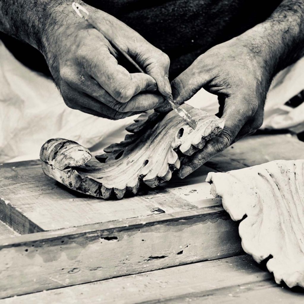 Hand-finishing ornate plaster cornice detail using traditional tools in workshop