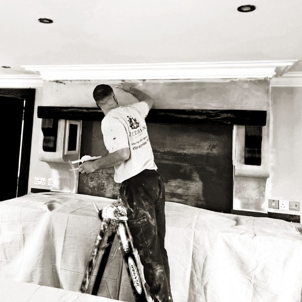Plaster cornice installation in progress with installer working at ceiling level on ladder
