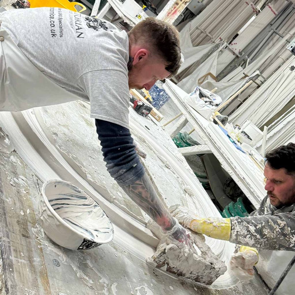 Craftsmen handcrafting bespoke plaster moulding in workshop