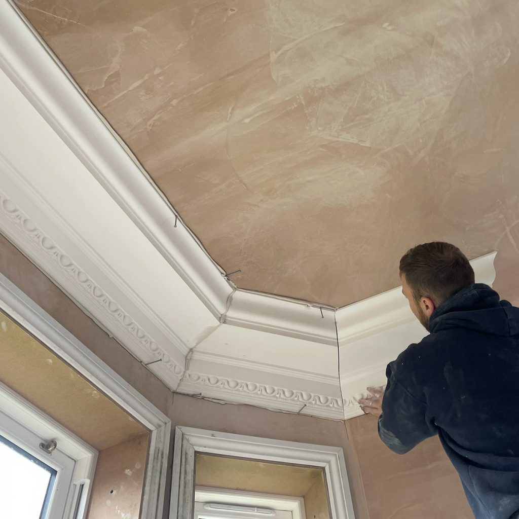 Installed plaster cornice around bay window showing clean joints and precise alignment
