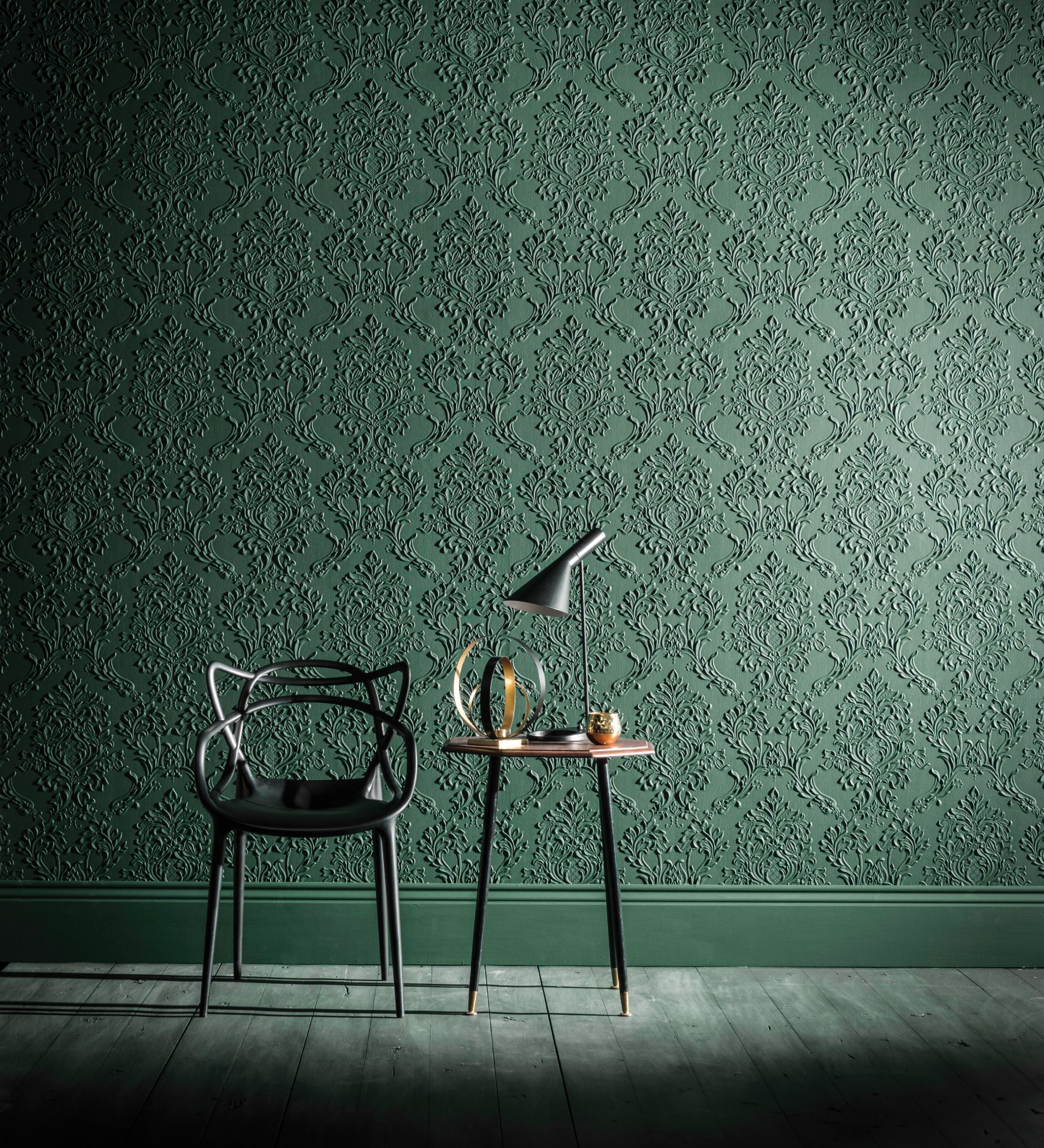 Green embossed Lincrusta damask wallcovering in a contemporary interior with black chair and side table