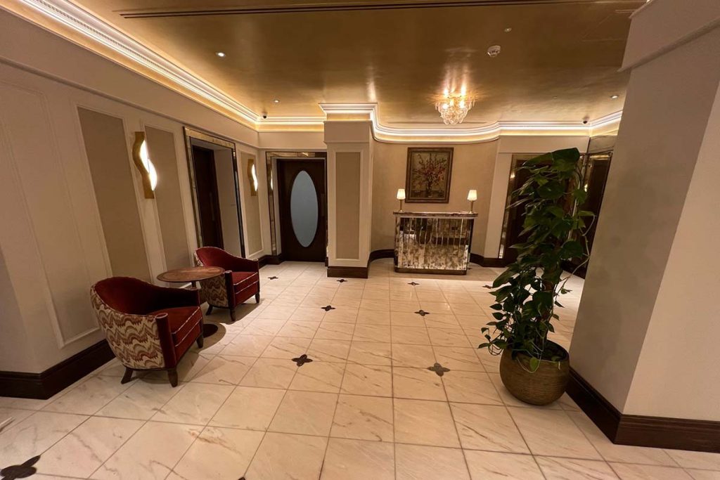 Luxury entrance lobby at The Sloane Club, London featuring bespoke plaster cornice, decorative wall panelling and concealed lighting.