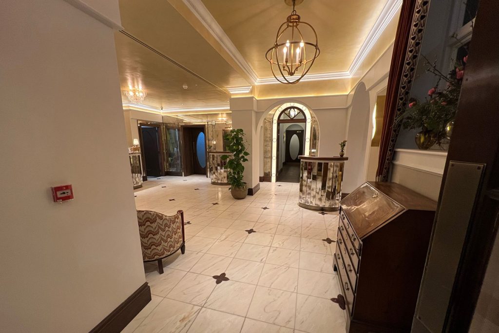 Grand reception area at The Sloane Club, London featuring bespoke plaster cornice, decorative arches and concealed LED lighting.