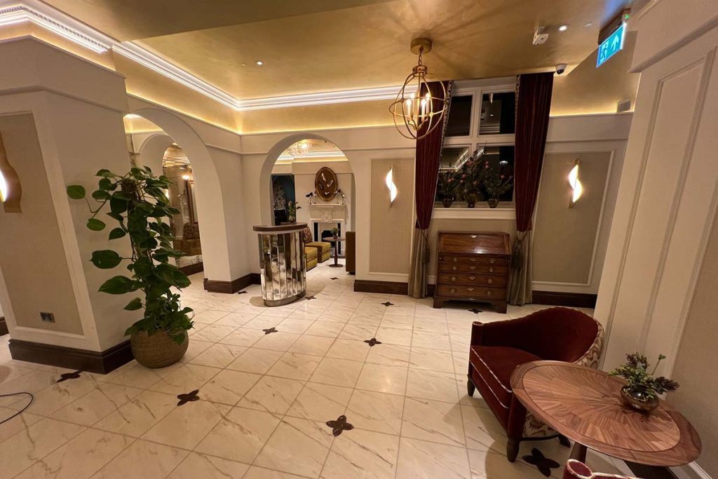 Reception lobby at The Sloane Club, London featuring bespoke curved plaster cornice, decorative wall panelling and concealed LED lighting.