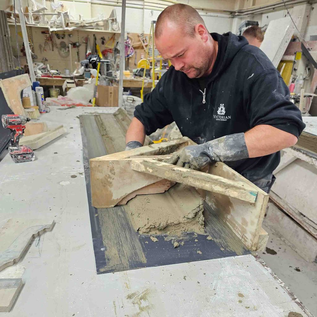 Craftsman handmaking exterior plaster cornice in the Victorian Cornice Company workshop using traditional fibrous plaster techniques.